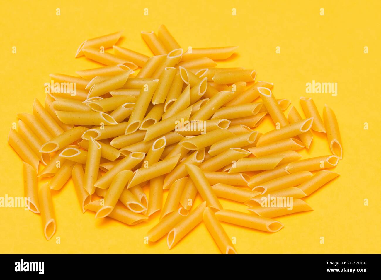 une poignée de macaronis non cuits sur fond orange. concept alimentaire, cuisine et mode de vie sain Banque D'Images