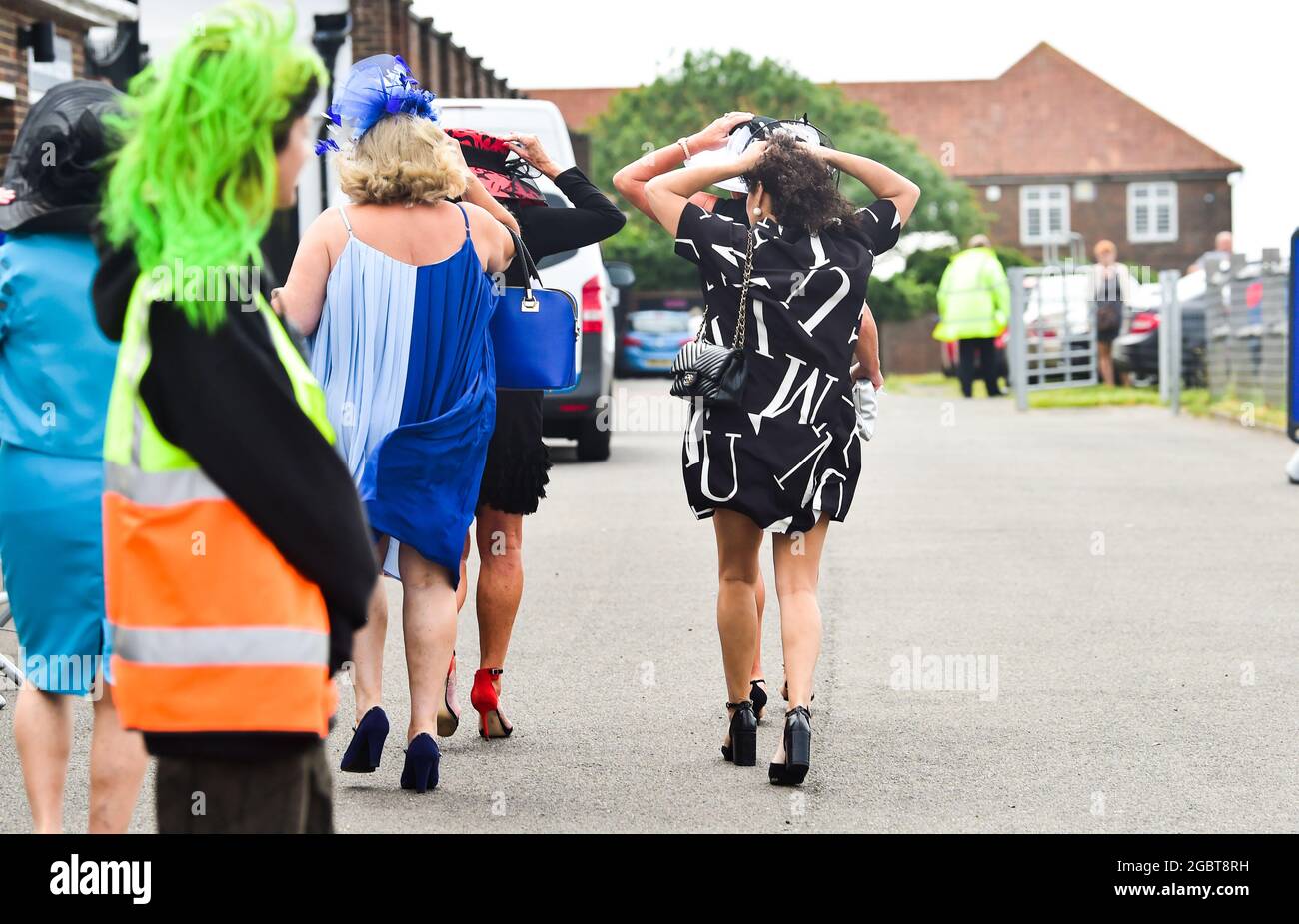 Brighton Royaume-Uni 5 août 2021 - les Racegoers s'accrochent à leurs chapeaux lorsqu'ils arrivent pour Brighton courses Ladies Day un après-midi de détente : Credit Simon Dack / Alay Live News Banque D'Images