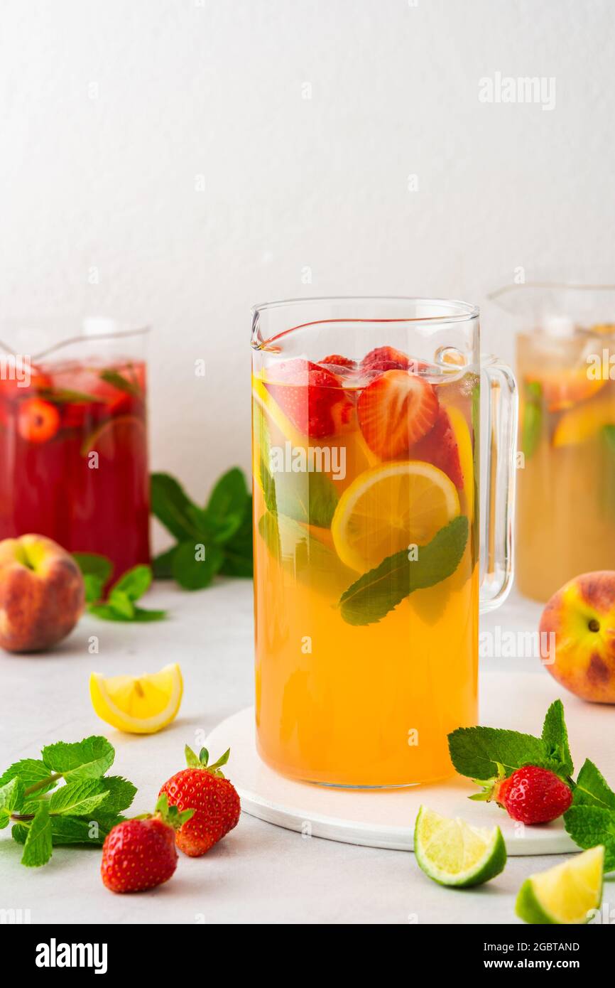 Cruches de boissons fraîches aux fruits avec quartiers de fruits, jus froids d'été avec glace Banque D'Images