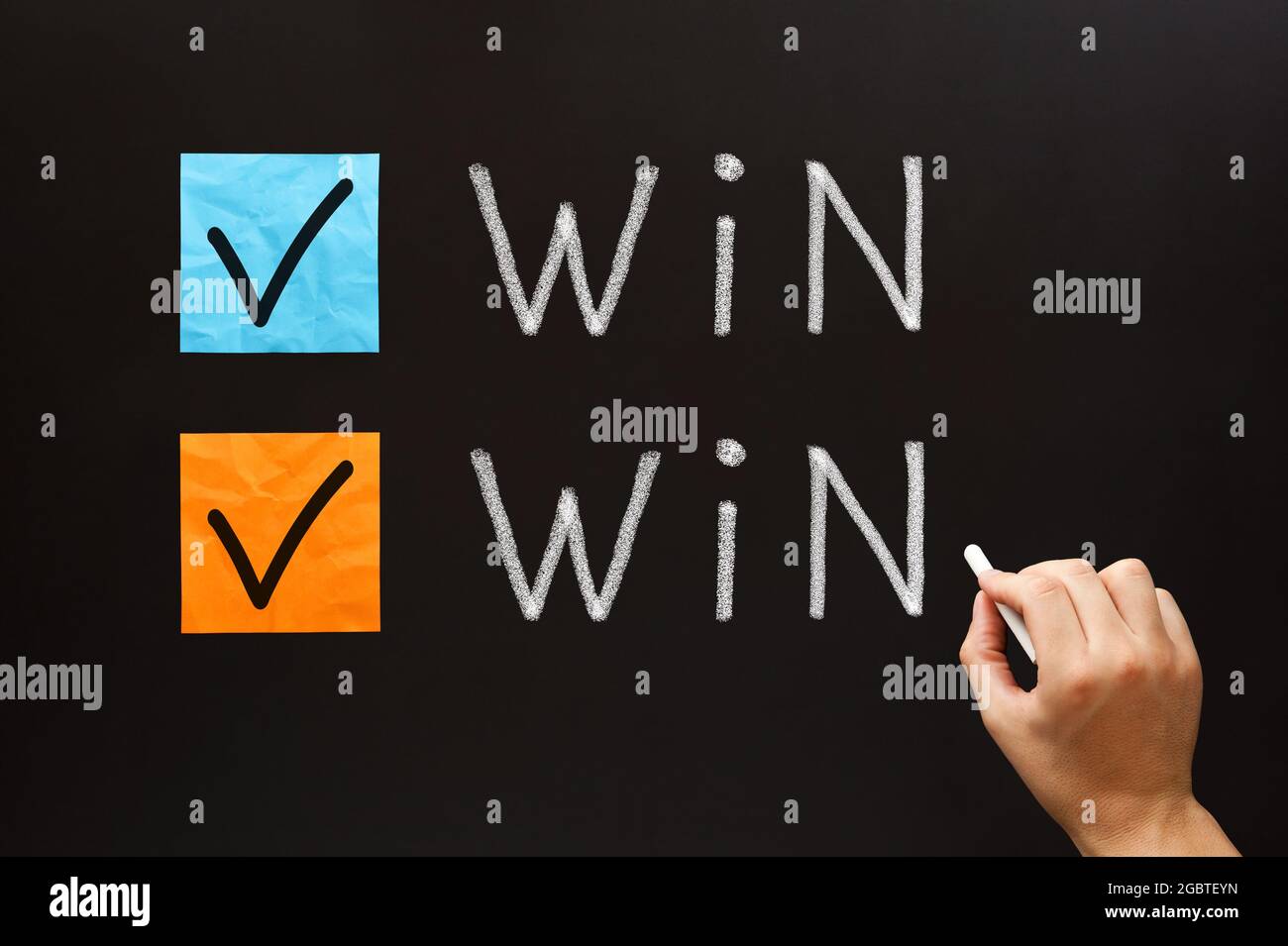 La main écrivant Win-Win situation business concept avec la craie blanche sur le tableau noir. Banque D'Images