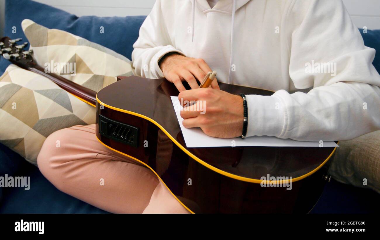 Mains d'un homme qui écrit sur un papier sur une guitare Banque D'Images