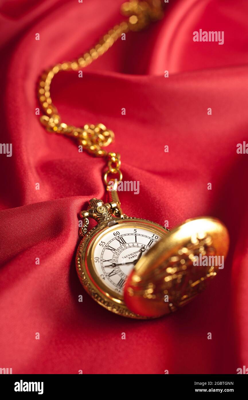montre classique de poche dorée avec chaîne sur soie rouge Banque D'Images