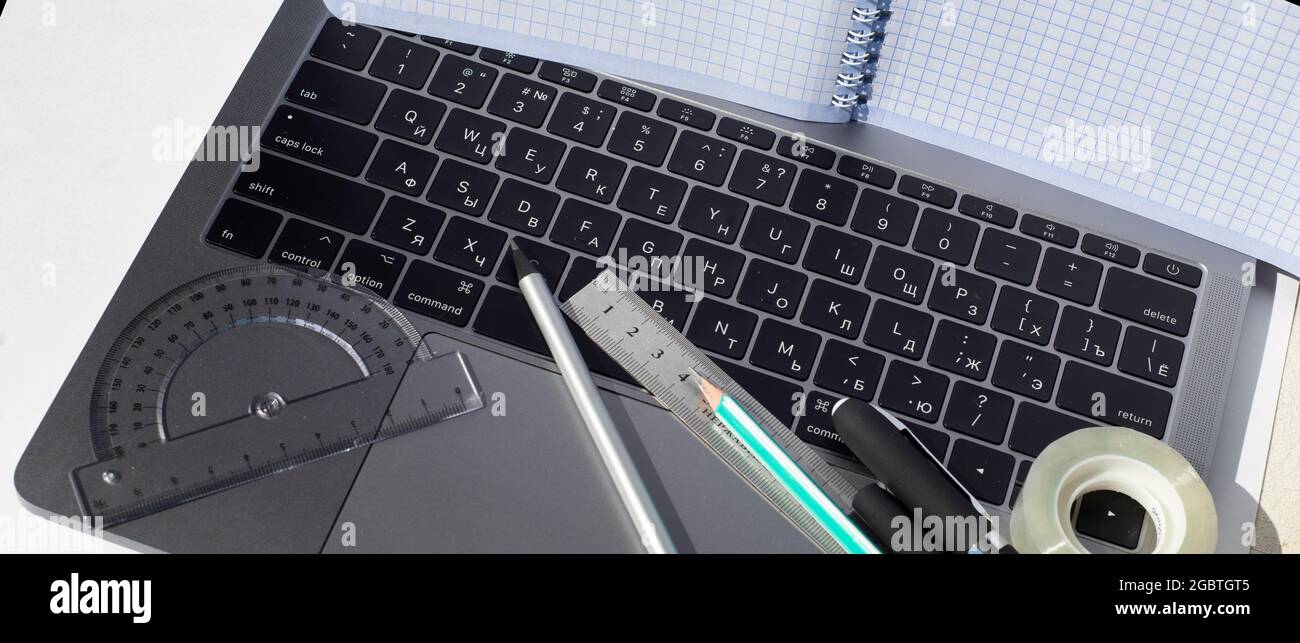 Un ordinateur portable à carreaux se trouve sur l'écran de l'ordinateur portable. Sur le clavier, les crayons, les stylos, la règle et le rapporteur. Thèmes de l'enseignement du travail de la finance Banque D'Images