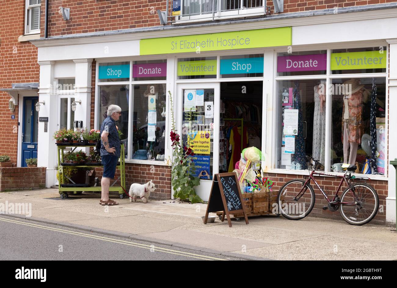 Hospice shop UK ; un homme debout devant le St Elizabeth Hospice Medical Charity Shop, Aldeburgh, Suffolk UK Banque D'Images