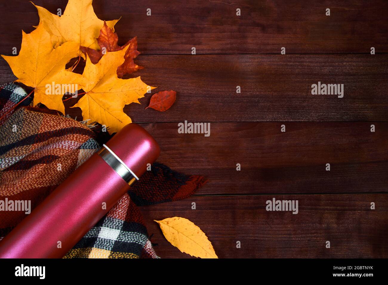 Étales d'automne. Thermos avec café chaud, écossais et feuilles mortes sur un fond en bois. Début de la saison d'automne. Copier l'espace. Banque D'Images