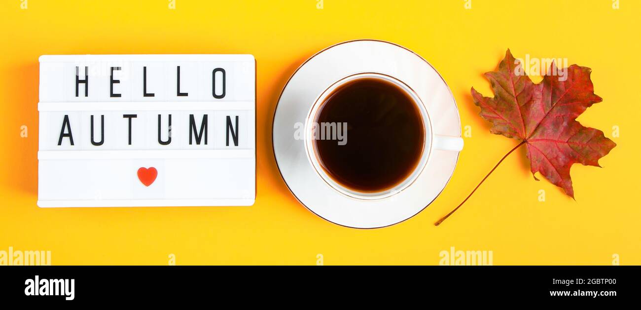Concept Hello Autumn. Tasse de café et un signe avec inscription sur fond jaune. Feuilles mortes et boisson chaude. Format de bannière Banque D'Images