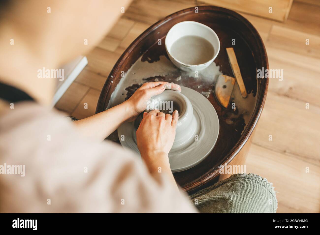 Vue de dessus de la poterie femme travaille dans le studio d'argile sur la roue de poterie. Fait à la main, conception et concept d'atelier. Banque D'Images