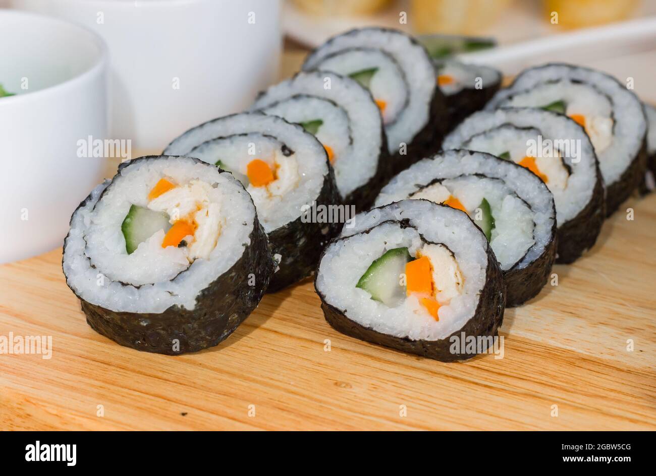 Maki de sushi végétarien avec riz, concombre, carotte et œuf sur une planche de bois Banque D'Images