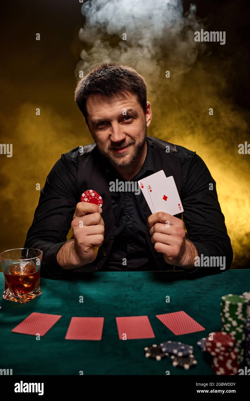 Joueur de casino barbu homme jouant au poker sur table verte Banque D'Images