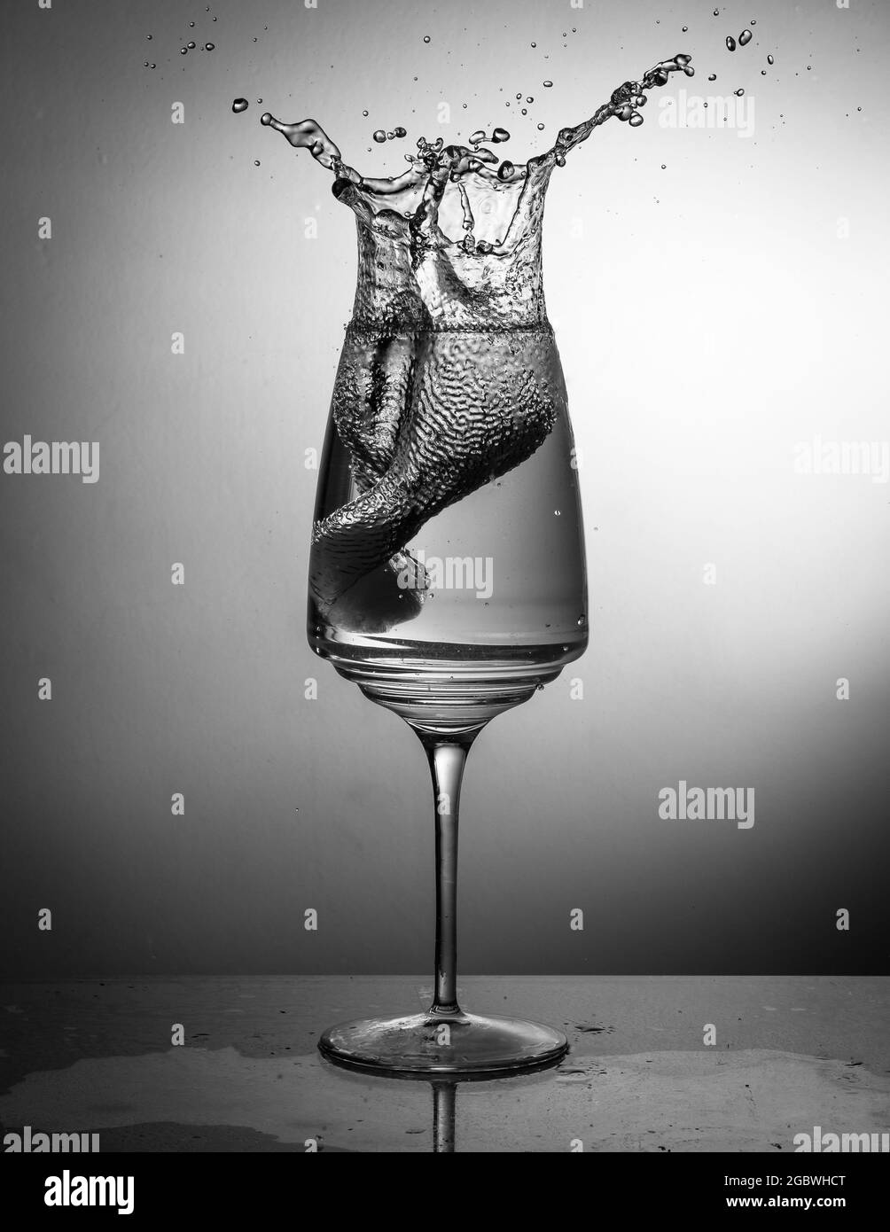 Prise de vue verticale en niveaux de gris d'un verre à vin avec éclaboussures d'eau Banque D'Images