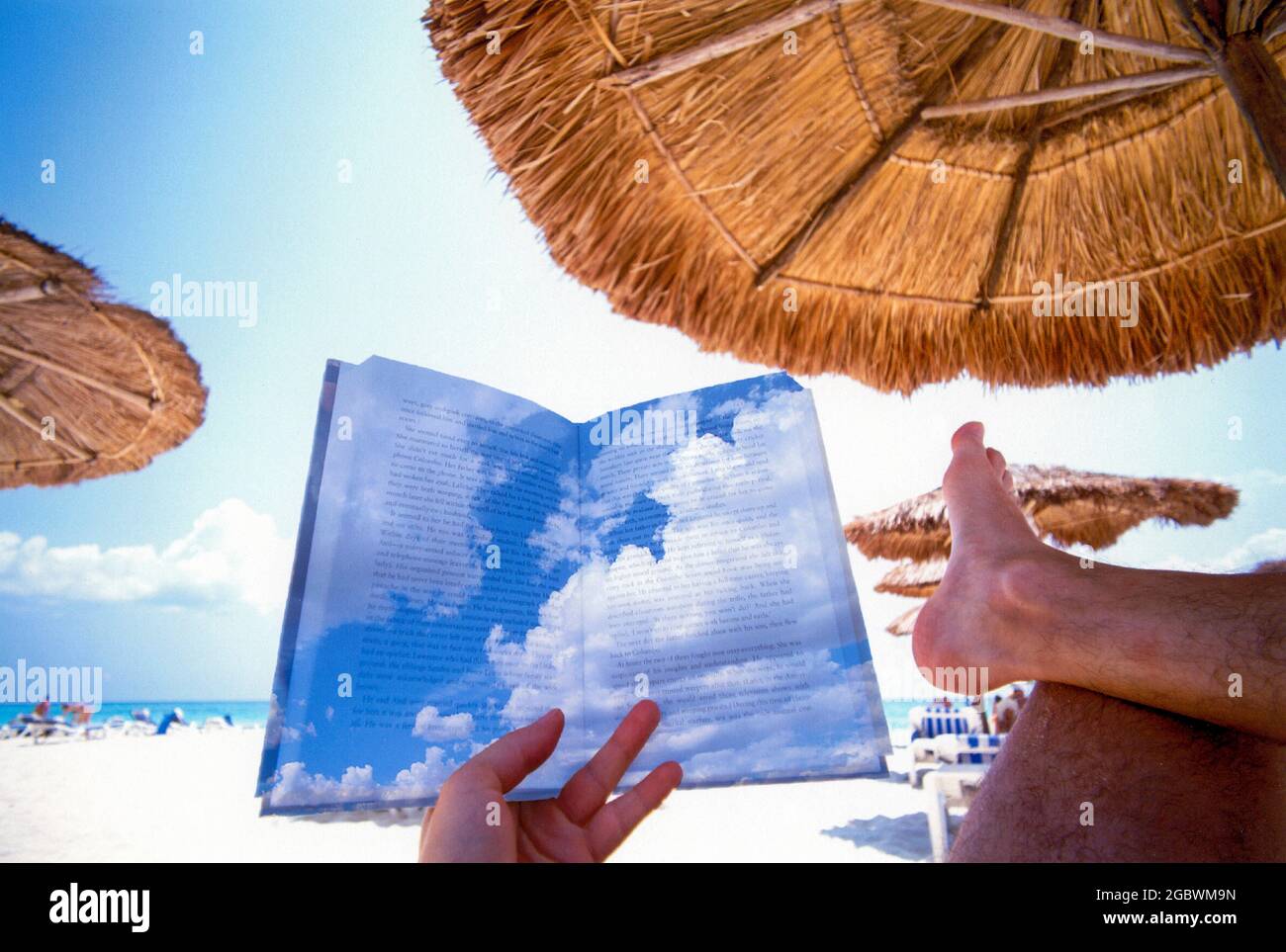 Vacances et détente, personne lisant un livre à une plage sous un palapa, image de concept avec des nuages superposés sur le texte pour rêver loin Banque D'Images