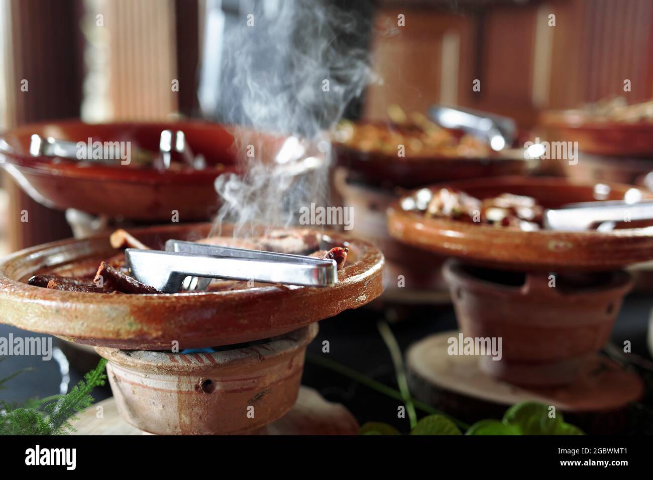 Aliments belges cuits placés dans des récipients en céramique avec un feu en dessous pour le maintenir au chaud. Banque D'Images