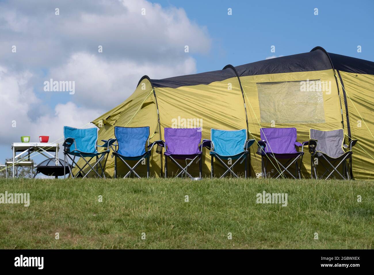 Une rangée de chaises de camping alignées sur une tente verte sur un site de camping du Lancashire, en Angleterre. Banque D'Images