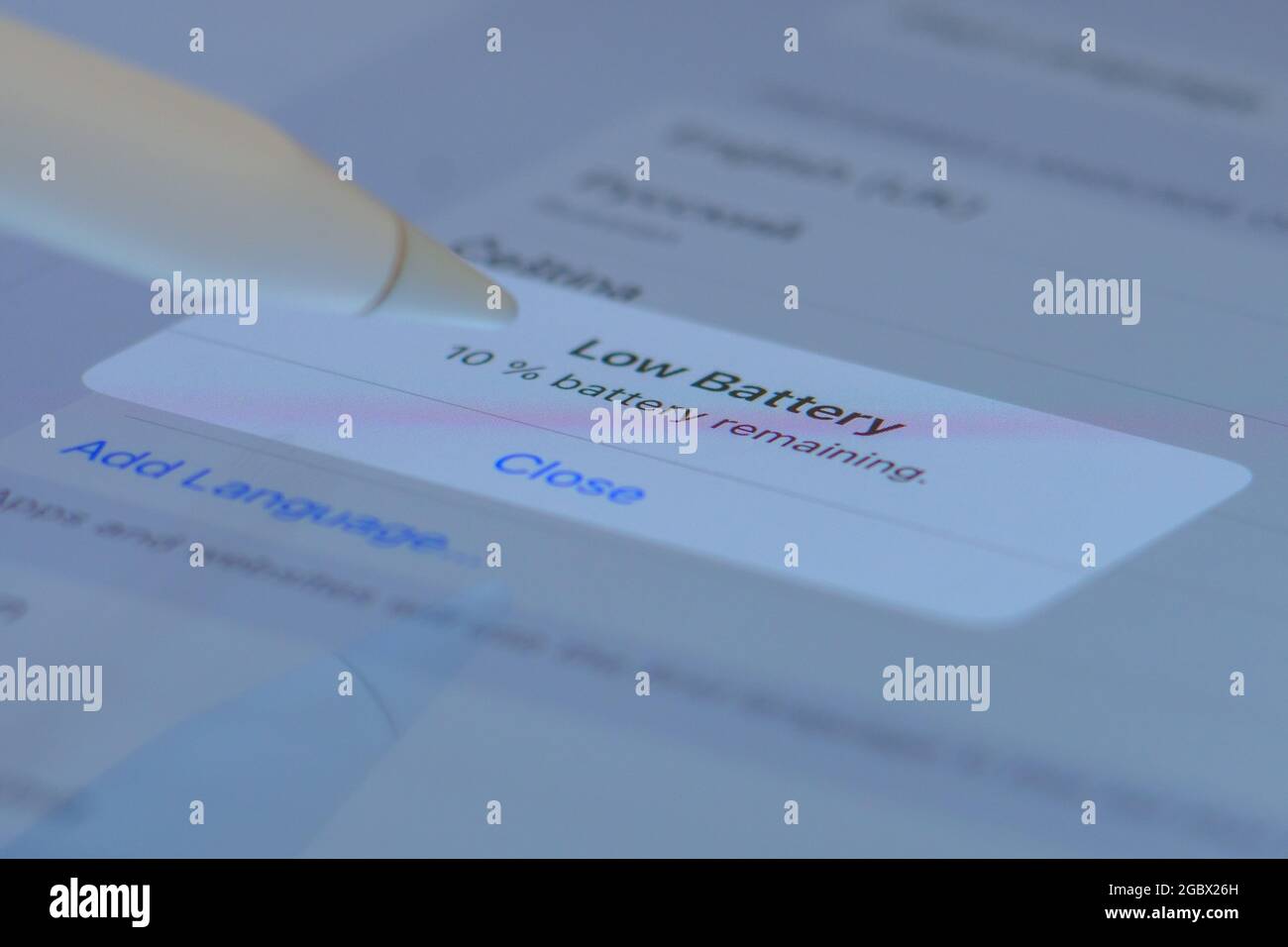Un crayon gros plan pousse la fenêtre de batterie faible sur l'écran de la tablette Banque D'Images