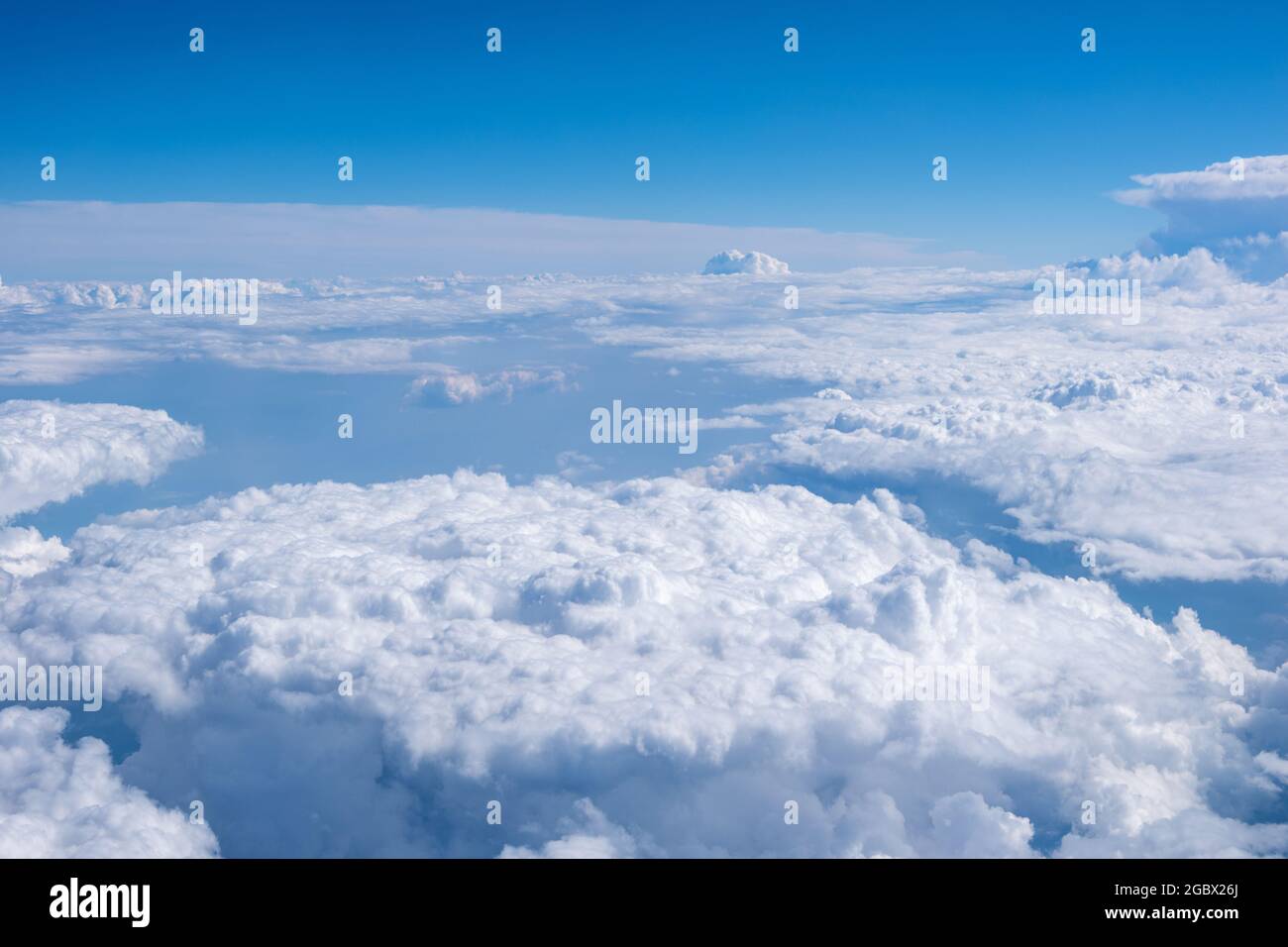Vue de dessus de la fenêtre de l'avion sur les magnifiques cumulus nuages blancs moelleux sur un ciel bleu avec un soleil lumineux. Fond d'écran ciel abstrait parfait Banque D'Images