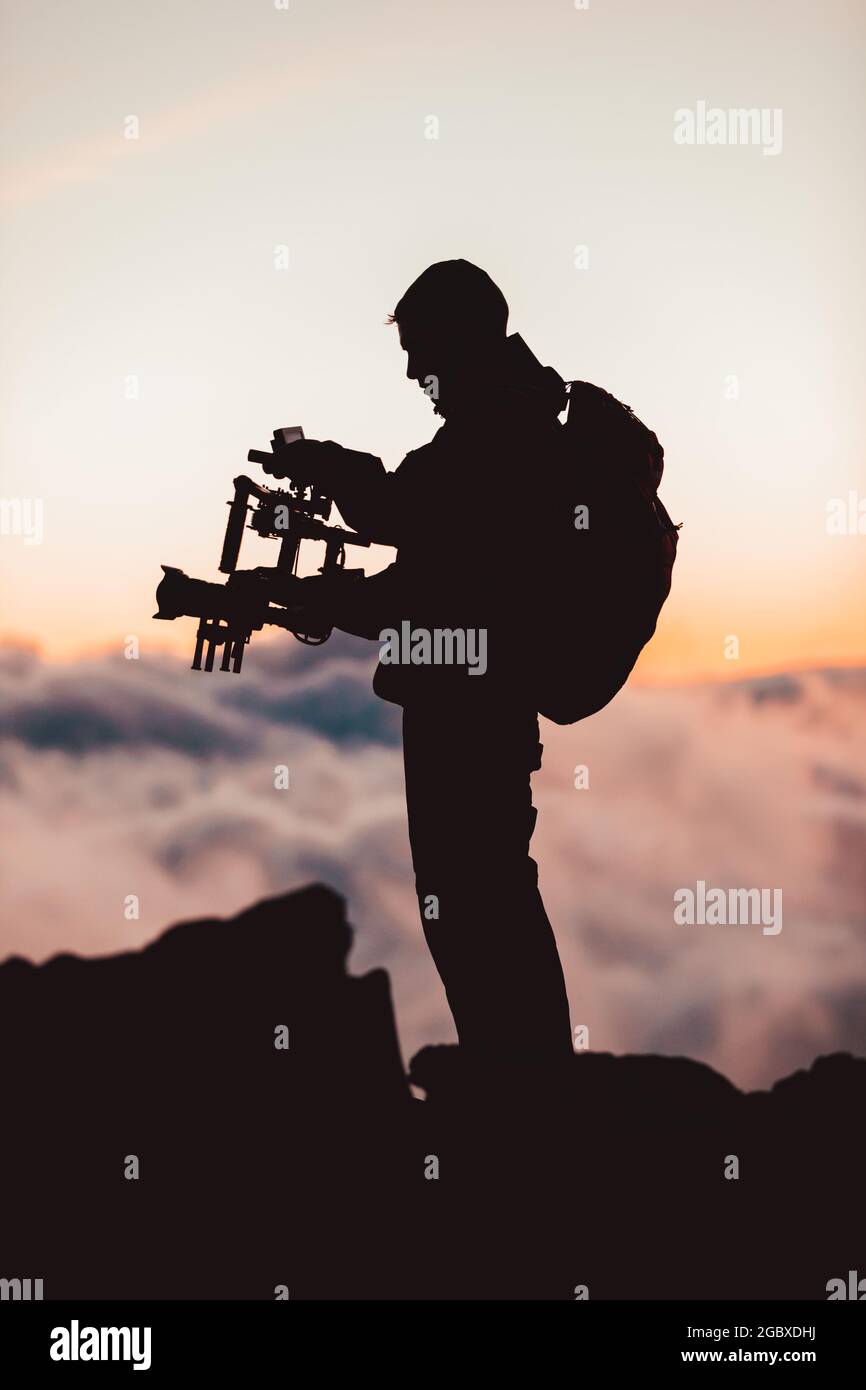 Homme vidéaste filmographie utilisant une caméra dlsr montée sur un stabilisateur de nacelle. Équipe de production vidéo pour le cinéma. Silhouette de Banque D'Images