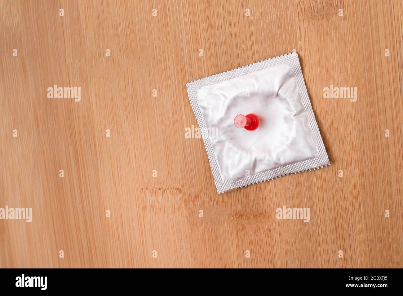 Une plaisanterie sur des collègues, Freebie ou un condom défectueux - Condom emballé de latex épinglé à un forum en bois Banque D'Images
