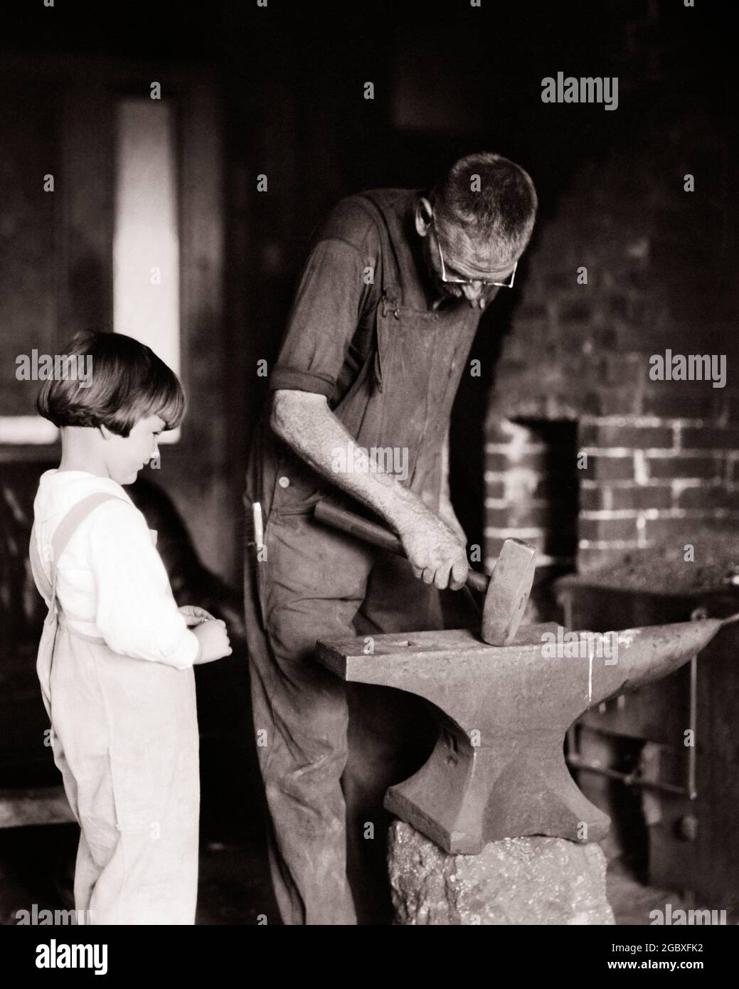 UN PETIT GARÇON DES ANNÉES 1920 REGARDANT UN HOMME TRAVAILLER SUR L'ENCLUME DU FORGERON - C334 HAR001 HARS GRAND-PÈRE GRANDS-PARENTS STYLE DE VIE GRANDS-PARENTS EMPLOIS MONTRANT RURAL COPY SPACE AMITIÉ DEMI-LONGUEUR PERSONNES INSPIRATION HOMMES PROFESSION ÂGE MOYEN B&W ÂGE MOYEN HOMME FORGE COMPÉTENCE RÊVES PROFESSION COMPÉTENCES DÉCOUVERTE FORCE CARRIÈRES SAVOIR FORGERON TRAVAIL FIERTÉ AUTORITÉ EMPLOI PROFESSIONS CONNEXION GRANDS-PÈRES CONCEPTUEL PETIT-FILS EMPLOYÉ ENVIL CRÉATIVITÉ IDÉES DE CROISSANCE JUVÉNILES NOIR ET RACE BLANCHE D'ORIGINE CAUCASIENNE GRANDPA HAR001 LABOURANT À L'ANCIENNE Banque D'Images