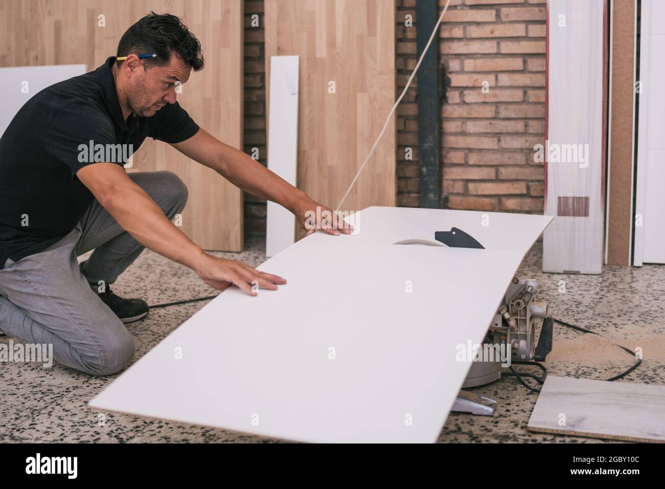 Homme non protégé coupant une surface avec un disque électrique dans un atelier Banque D'Images