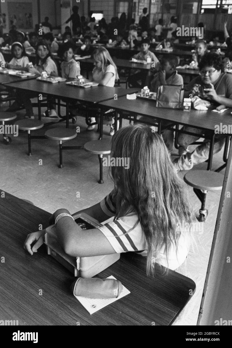 Austin Texas USA, vers 1990: Une jeune fille de cinquième année est assise par elle-même pendant le déjeuner à la cafétéria de l'école élémentaire. ©Bob Daemmrich Banque D'Images