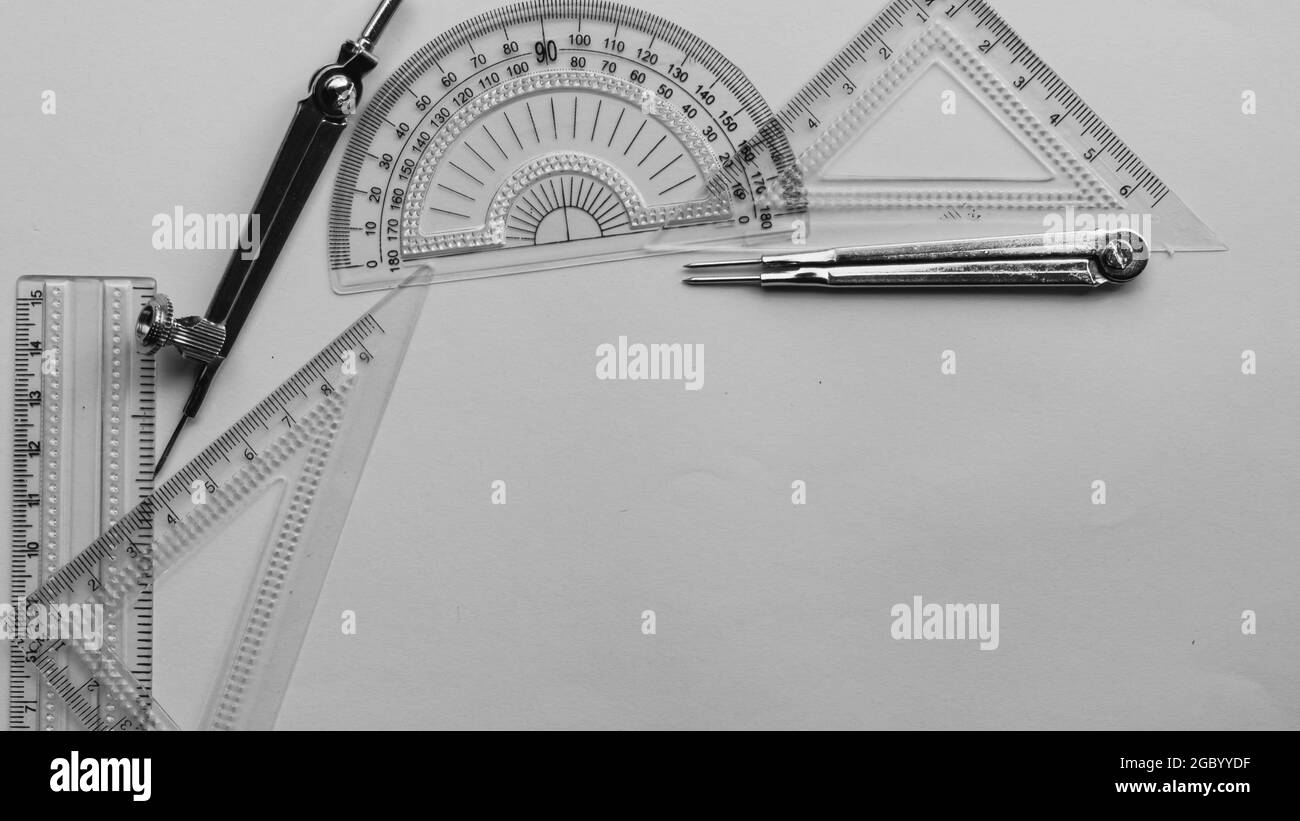 Outils de mesure géométrique, éléments de dessin et instruments mathématiques placés sur une feuille de papier blanc. Retour à l'école et formation en génie b Banque D'Images