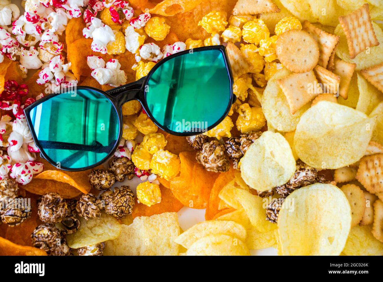 Croustilles de pop-corn salées et sucrées et lunettes de soleil sur fond blanc, vue en angle bas Banque D'Images