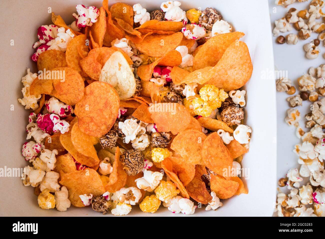 Pop-corn salé et sucré et croustilles sur fond blanc, vue en angle bas Banque D'Images