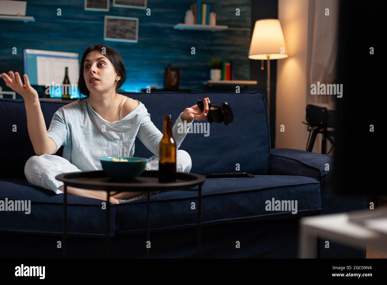 Colère déçue femme tenant le joystick de jeu jouant des jeux vidéo de football à la télévision perdant en ligne jeux vidéo concurrence. Personne expressive frustrée qui se délasser dans un pyjama relaxant tard dans la nuit Banque D'Images