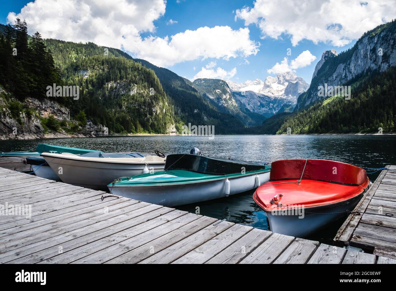 Ligne de bateaux colorés sur les quais d'un lac à Dachstein, Autriche entouré de collines verdoyantes Banque D'Images