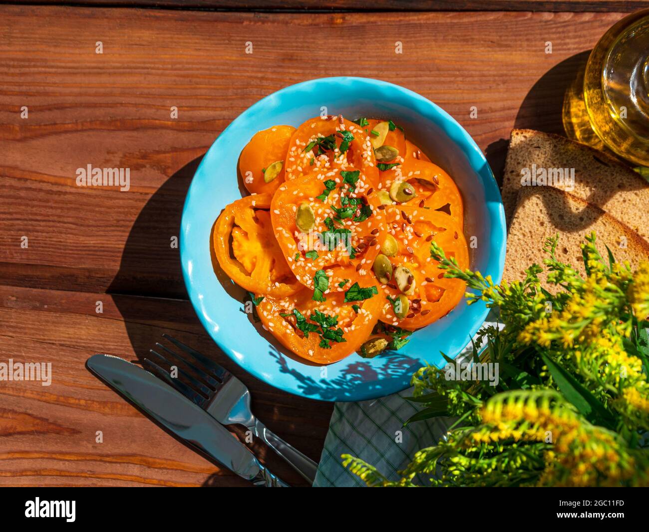 Salade de tomates jaunes avec tranches de pain de seigle dans un bol en céramique bleu vue du dessus. Légumes frais mûrs colorés mélangés de tranches de légumes avec du vinaigre d'huile d'olive p Banque D'Images