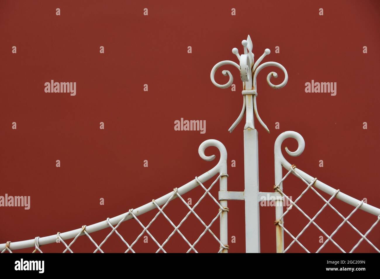 Clôture en fer forgé avec bouts sur un mur de fond rouge Photo Stock