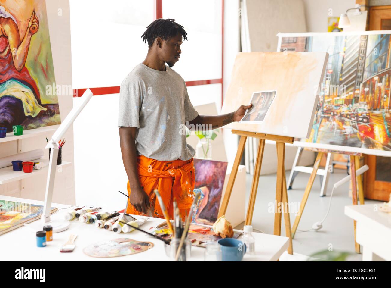 Un peintre afro-américain au travail tenant une photo dans un studio d'art Banque D'Images