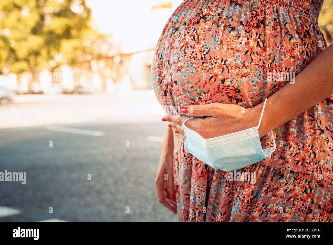 Gros plan d'un ventre enceinte avec un masque facial dans sa main. Banque D'Images