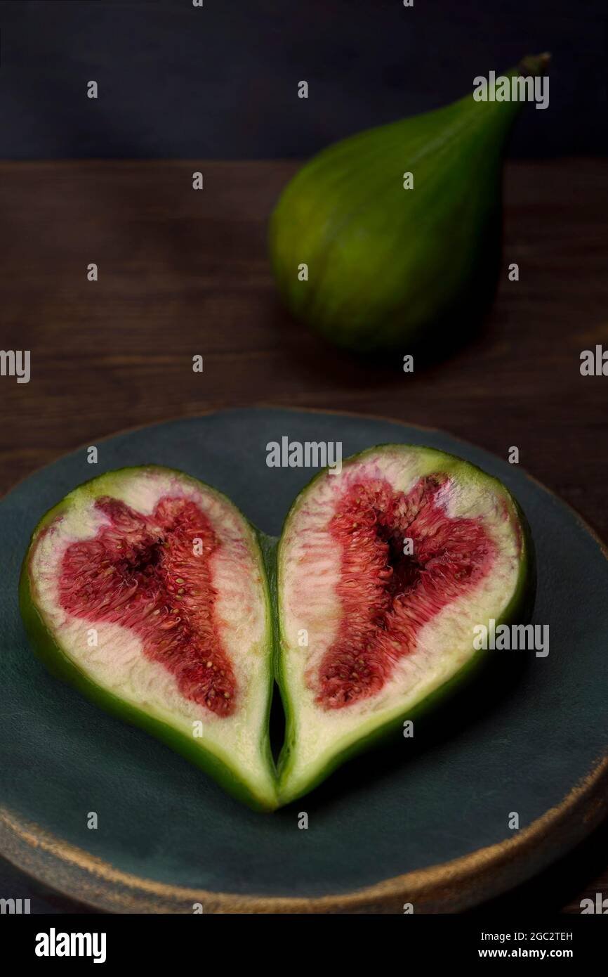 Figues ​​ripe en tranches dans une plaque d'époque en bronze bleu-vert sur une table en bois sous les rayons de lumière. Vue de dessus Banque D'Images