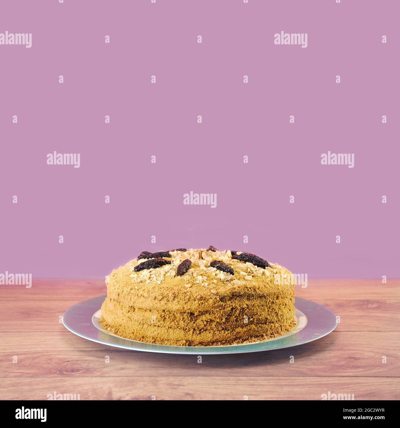 Gâteau fait maison avec crème, noix et pruneaux sur une table en bois sur fond violet avec espace copie Banque D'Images