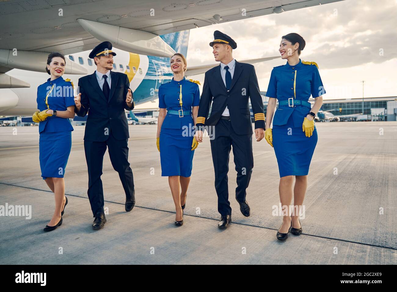 Belles hôtesses et belles aviateurs marchant le long de l'aérodrome Banque D'Images