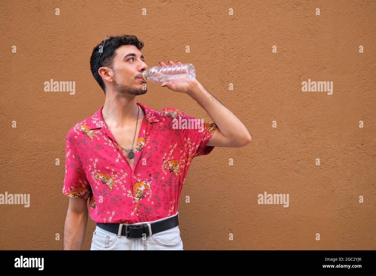 Jeune homme caucasien avec de longs ongles faux buvant de l'eau dans la rue. Banque D'Images