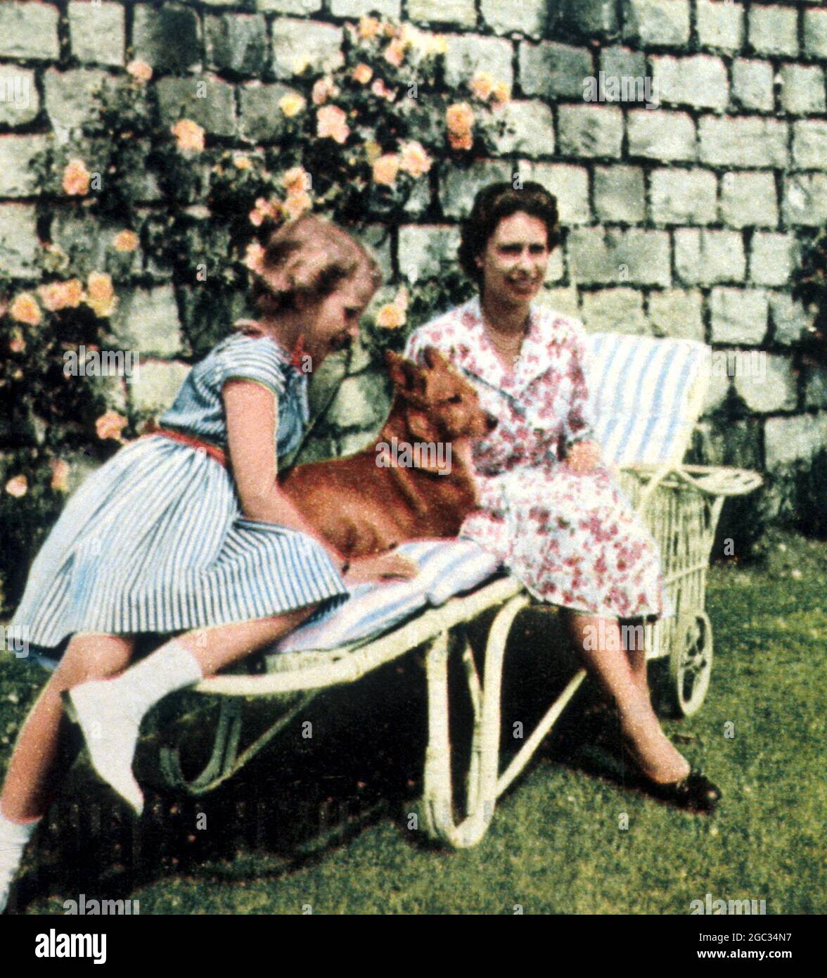 La reine Elizabeth II avec la princesse Anne en 1960 se détendre dans le jardin, partager un transat avec un des corgis Banque D'Images