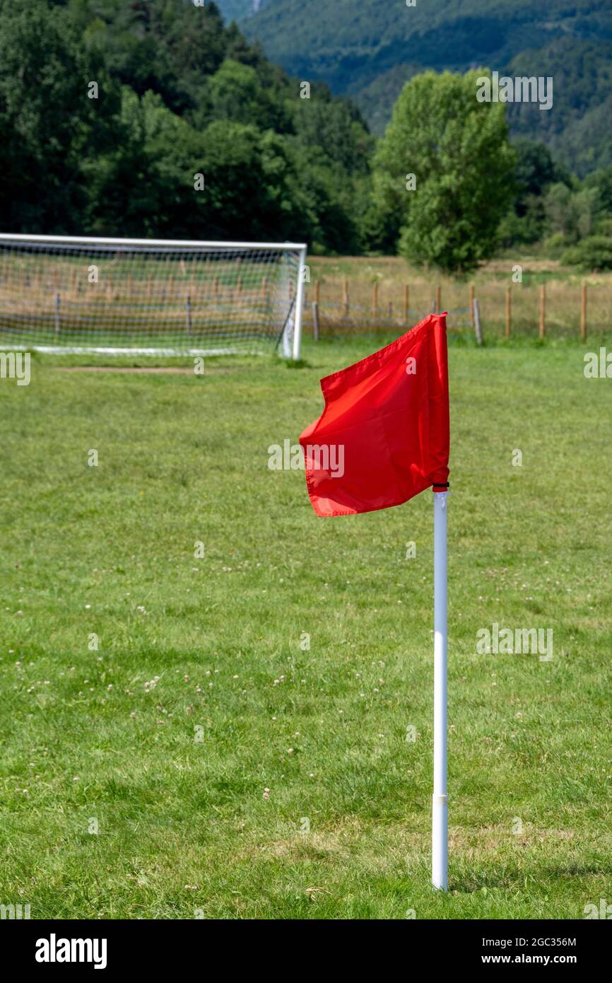 Un drapeau rouge se dresse sur un terrain de football verdoyant dans un cadre serein de campagne pendant un après-midi ensoleillé Banque D'Images