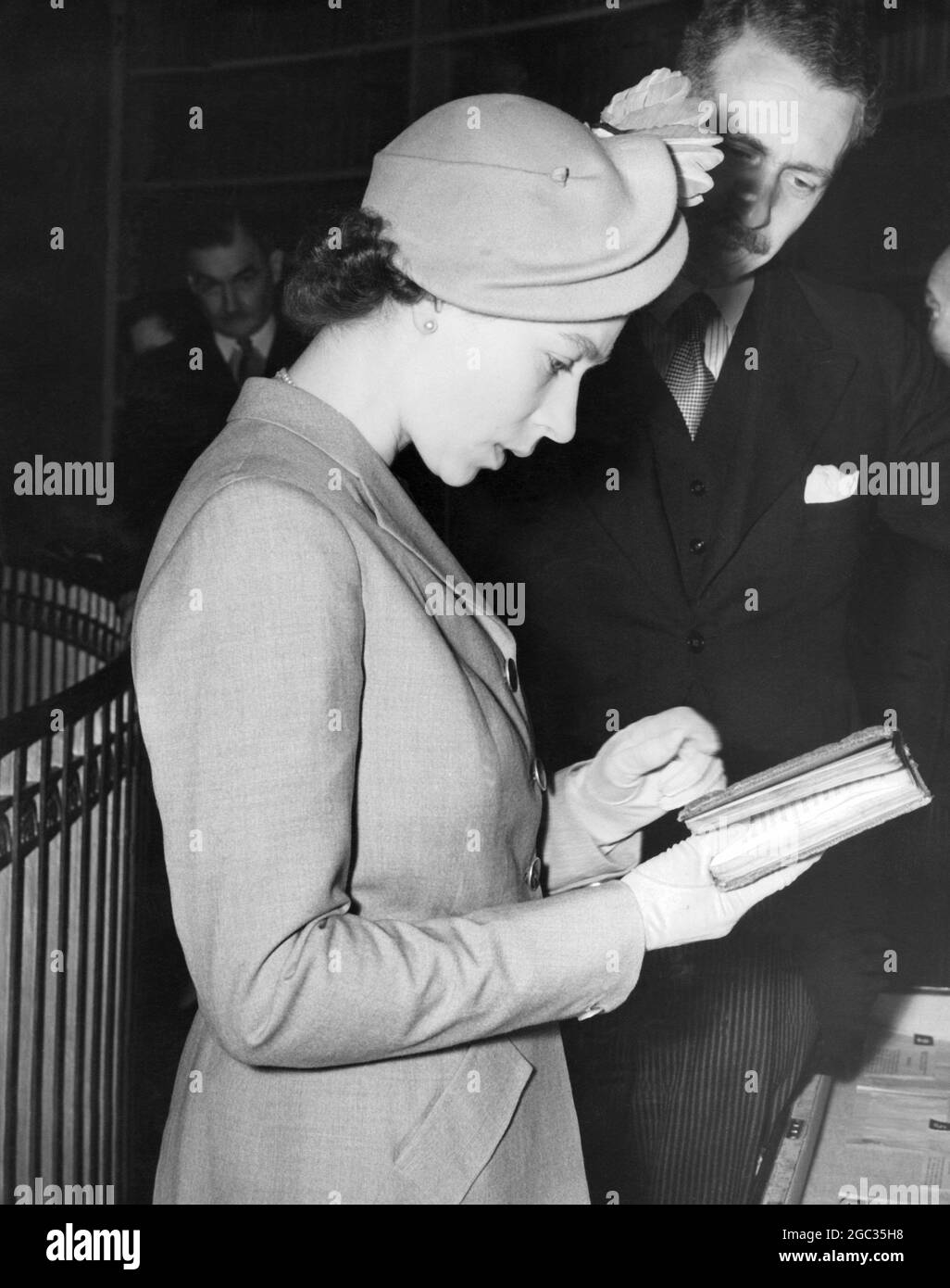 La Reine (Elizabeth II) a visité le Register House, à Édimbourg, où se trouvent des documents écossais et des documents historiques et où se trouve un musée dans la Dome Gallery. Ici, elle est dans la Dome Gallery regardant un livre écrit à la main par Elizabeth I (bonne reine Bess) quand elle était une princesse vers le 1545 27 juin 1952 Banque D'Images