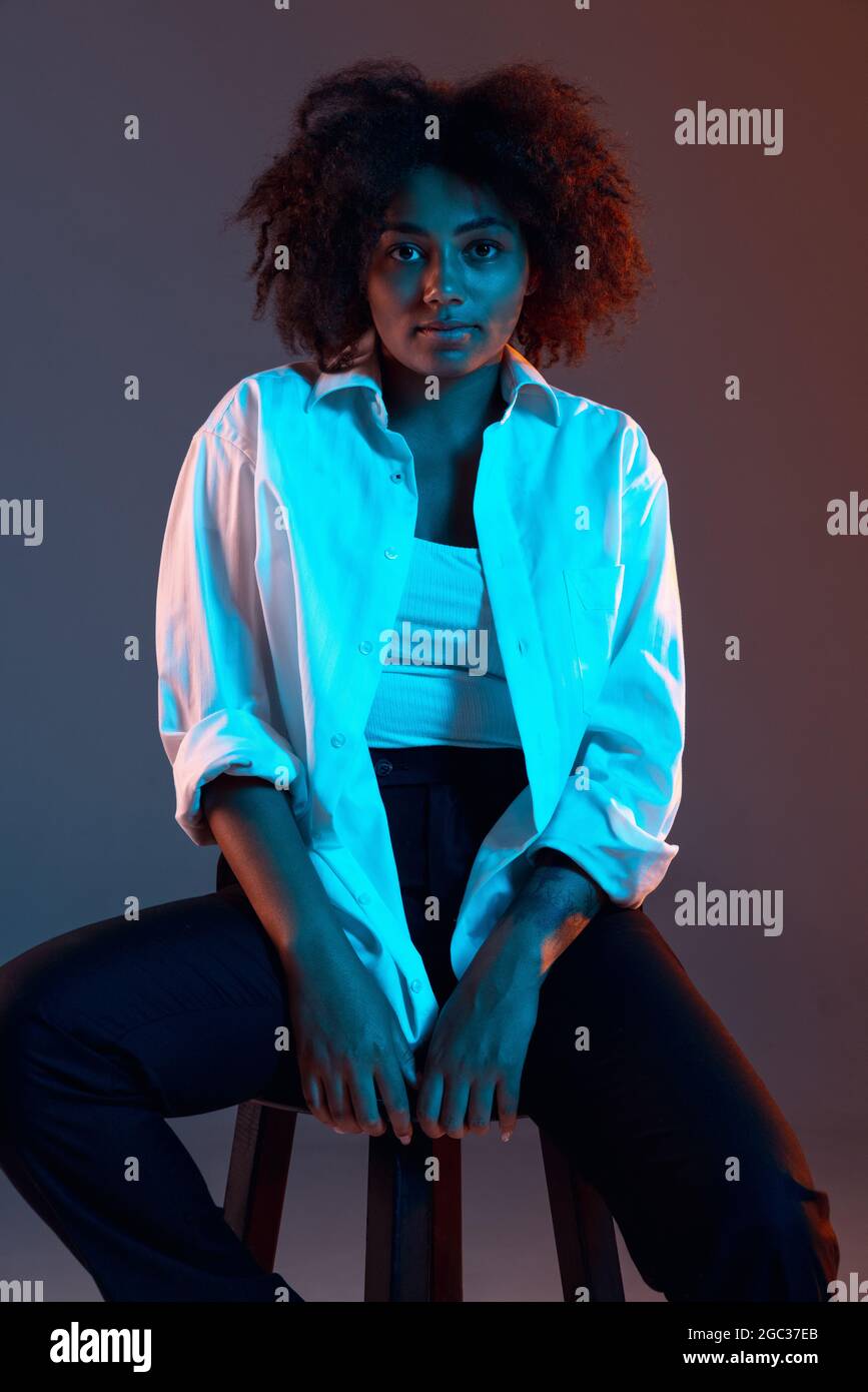Portrait complet de la jeune fille africaine vetements decontractes tenue isolee sur fond bleu fonce studio dans lumiere rose neon. Concept de l homme Photo Stock Alamy