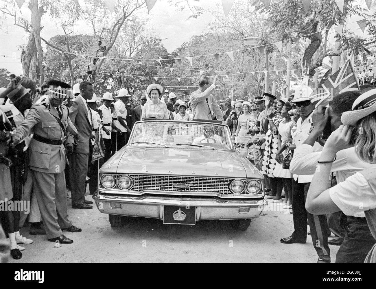 Barbade : Grande-Bretagne la reine Elizabeth II et le prince Philip Duke d'Édimbourg, actuellement en tournée de cinq semaines dans les Caraïbes, sont photographiés en voiture à travers Queens Park après leur arrivée à la Barbade, le 14 février. 16 février 1966 Banque D'Images