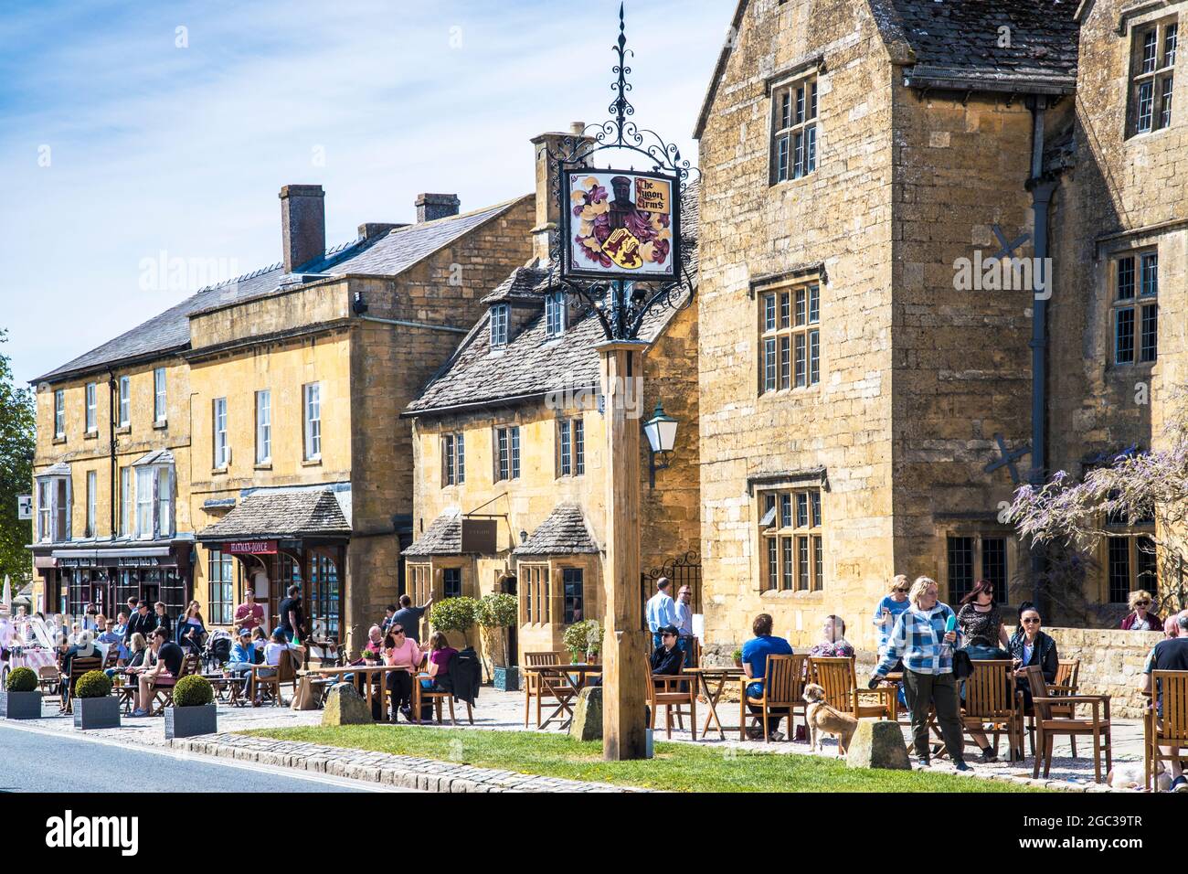 Les gens profitent du soleil de printemps, à l'extérieur d'un pub dans la ville de Broadway, dans le Cotswold, dans le Worcestershire. Banque D'Images