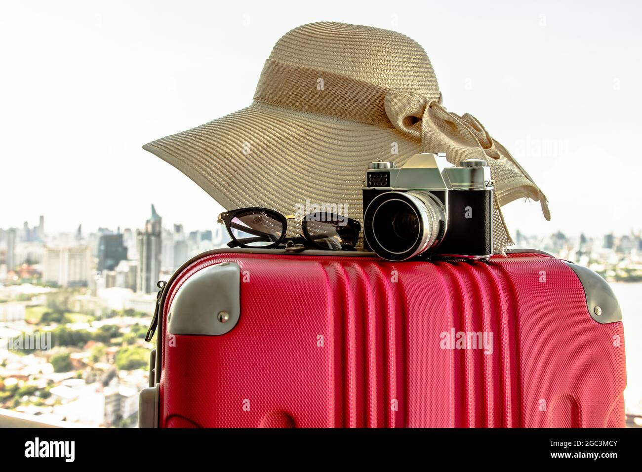 Vacances et voyages. Valise ou sac à bagages avec chapeau, appareil photo  et lunettes de soleil avec fond de vue sur la ville. Vacances d'été  vacances en voyage Desi Photo Stock -
