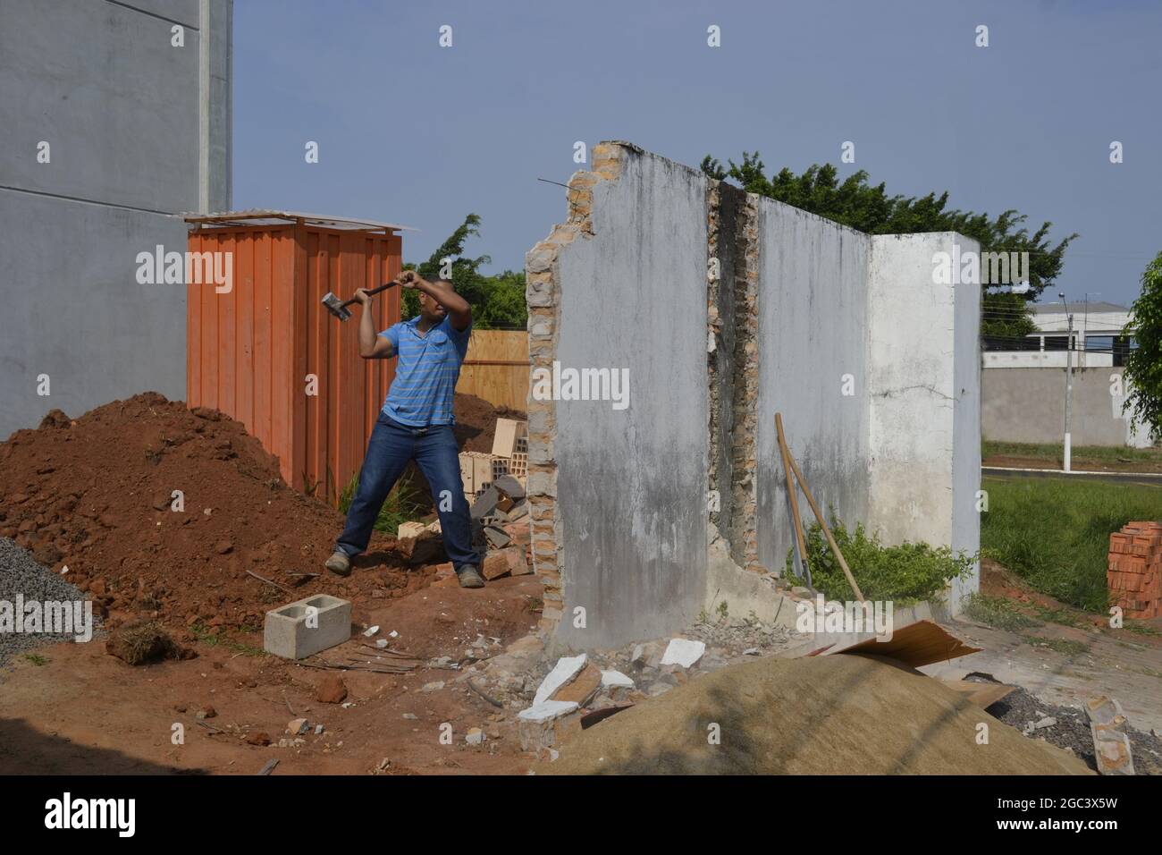Calque de briques. Ouvrier démolissant le mur blanc avec un marteau en traîneau en construction pour rénover la zone au Brésil, en Amérique du Sud en vue panoramique Banque D'Images