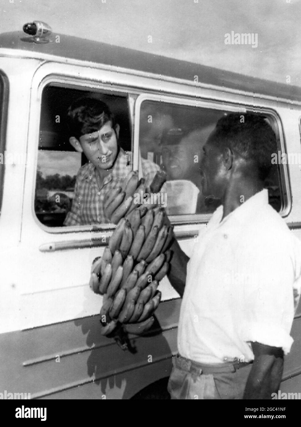 Le missionnaire anglican de Papuan, le père Hennington, offre au prince Charles un bâton de bananes à sa mission à Popondetta, près de Dogura, où le prince et une partie de 25 autres garçons de l'école de grammaire de Geelong sont en visite de onze jours. Mai 1966 Banque D'Images