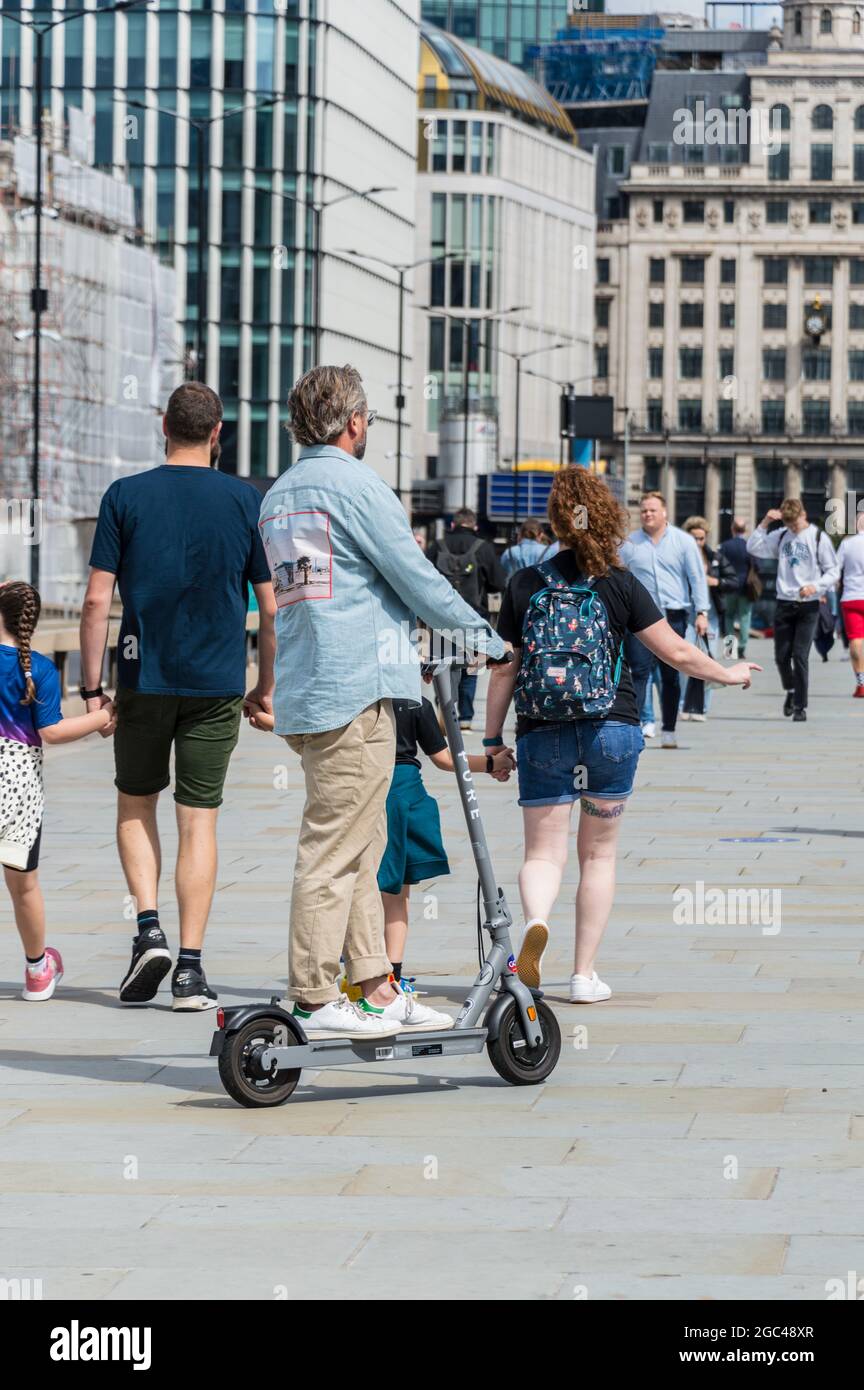 E-scooter privé un monté sur la chaussée par l'homme d'âge moyen qui esquive les piétons Banque D'Images