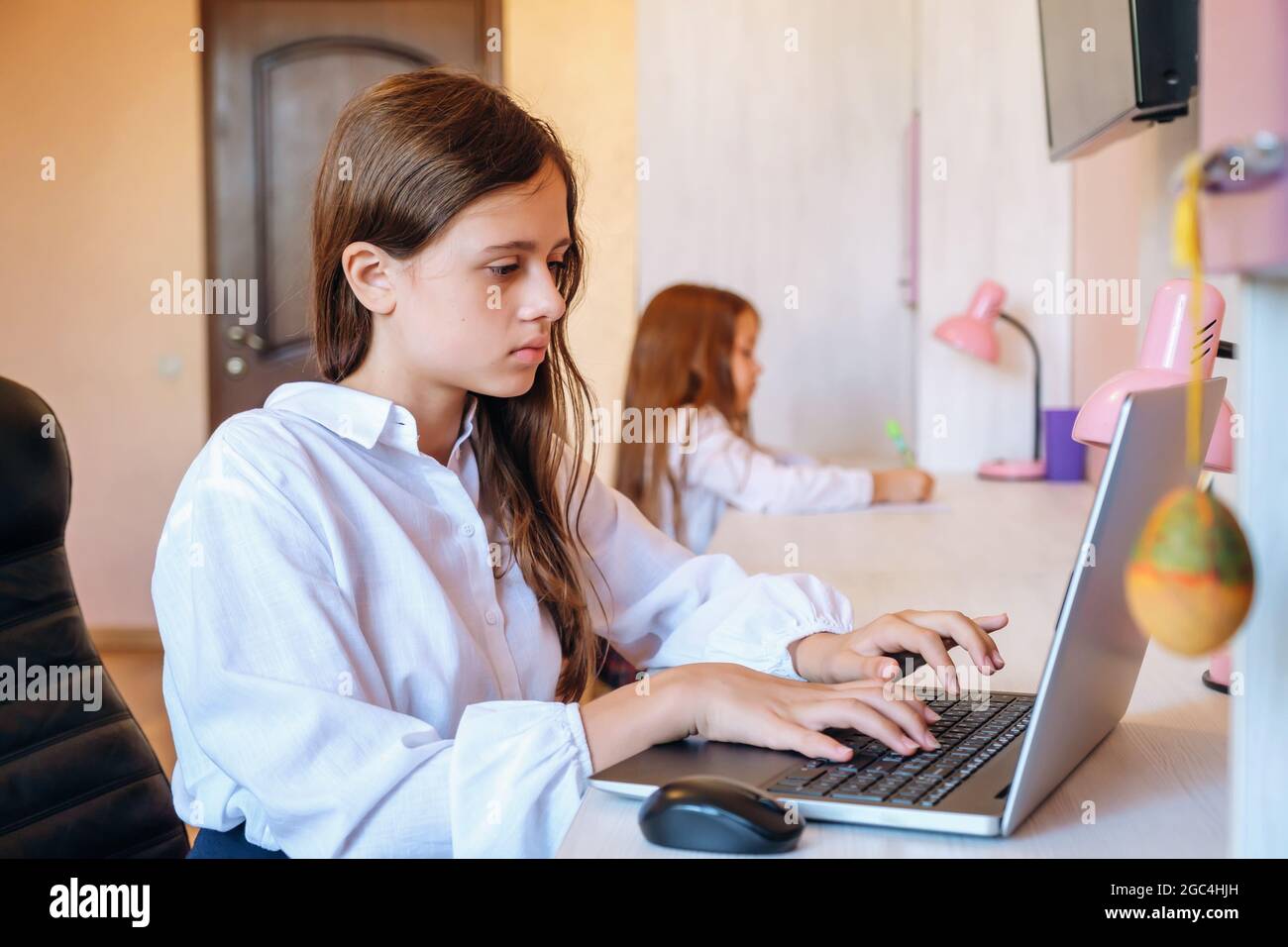 Une écolière étudie ses devoirs pendant sa leçon en ligne à la maison Banque D'Images