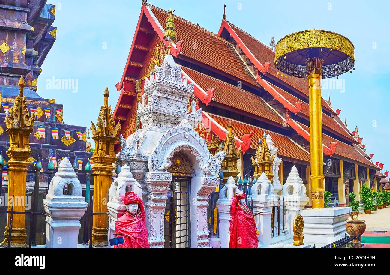 Le toit de Pyathat (pignon) du Viharn Luang est vu derrière le parapluie de cérémonie de chatra doré et la porte de stuc du Chedi de Wat Phra que Lampang Banque D'Images