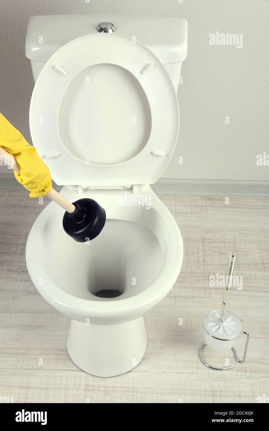 Femme utilise un piston pour déboucher une cuvette des toilettes dans une  salle de bains Photo Stock - Alamy
